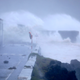 Waves crash on a seafront road in Horta.